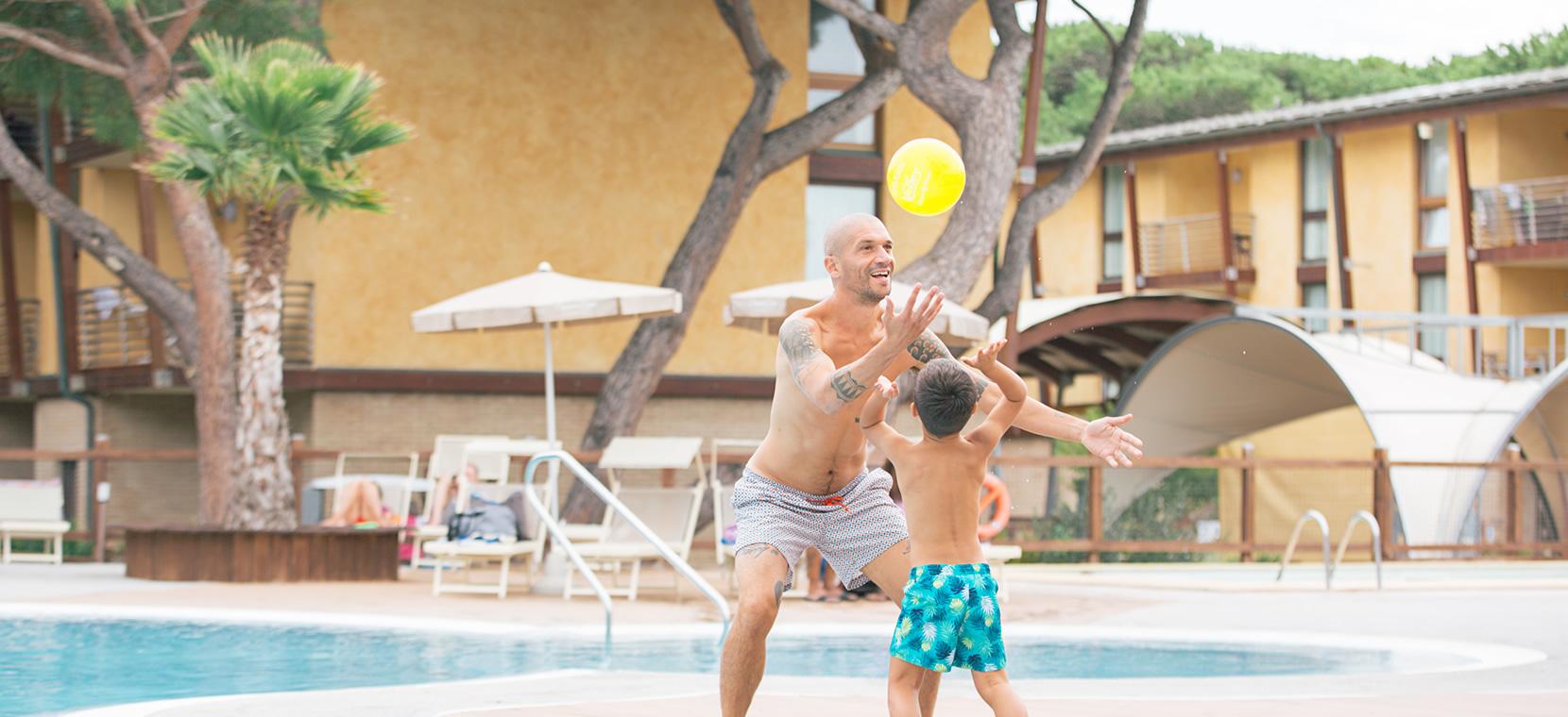 Vater und Sohn spielen Frisbee am Pool.