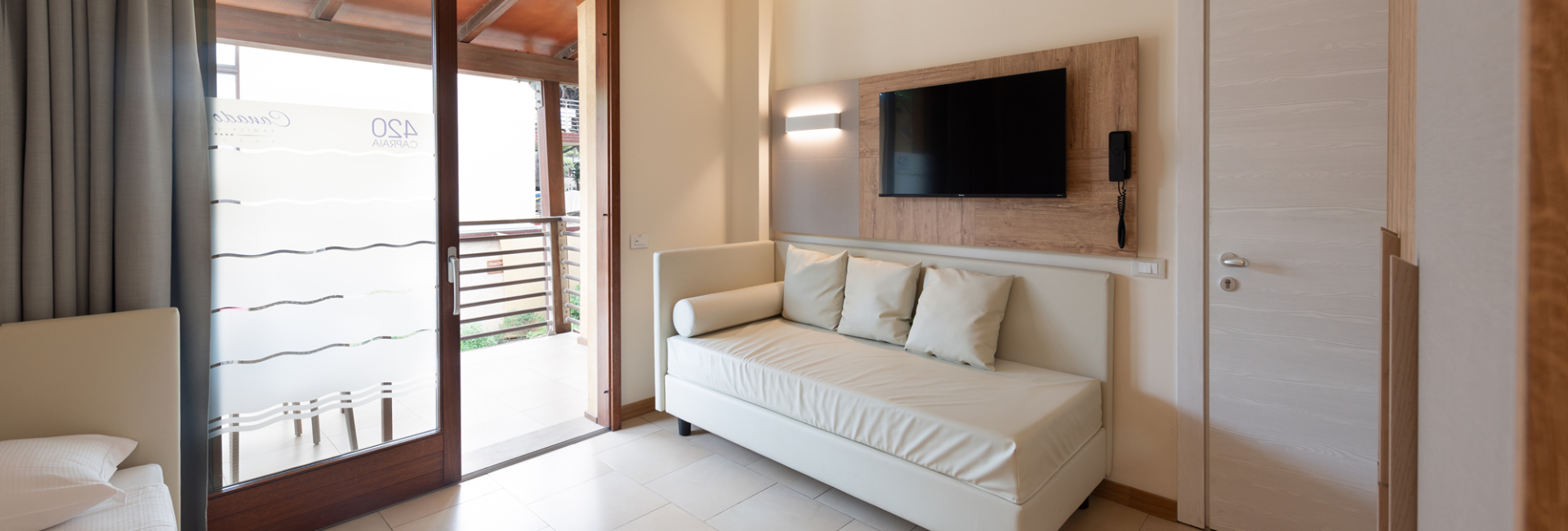 Modern room with sofa, TV, and balcony.