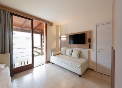 Modern room with sofa, TV, and balcony.