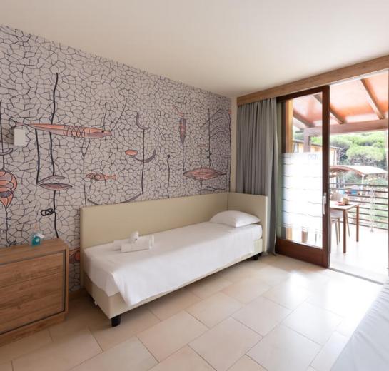 Bright room with single bed and balcony, decorated with fish murals.