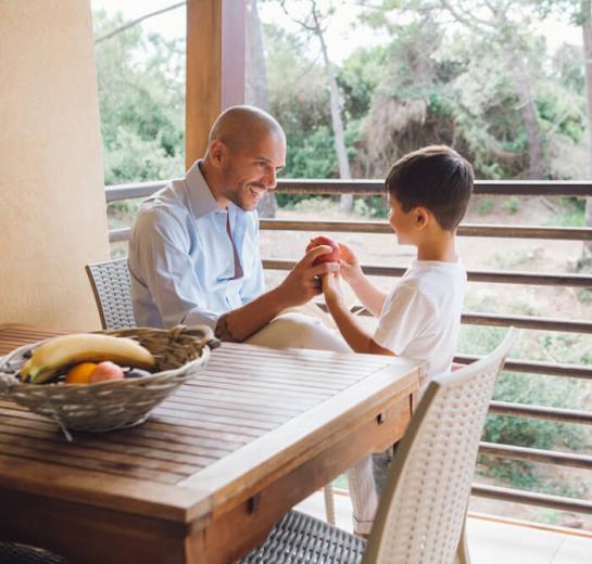 Padre e figlio giocano con una mela sul balcone.