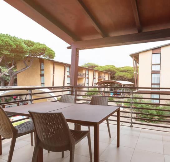 Terrazza con tavolo e sedie, vista su edifici e alberi.