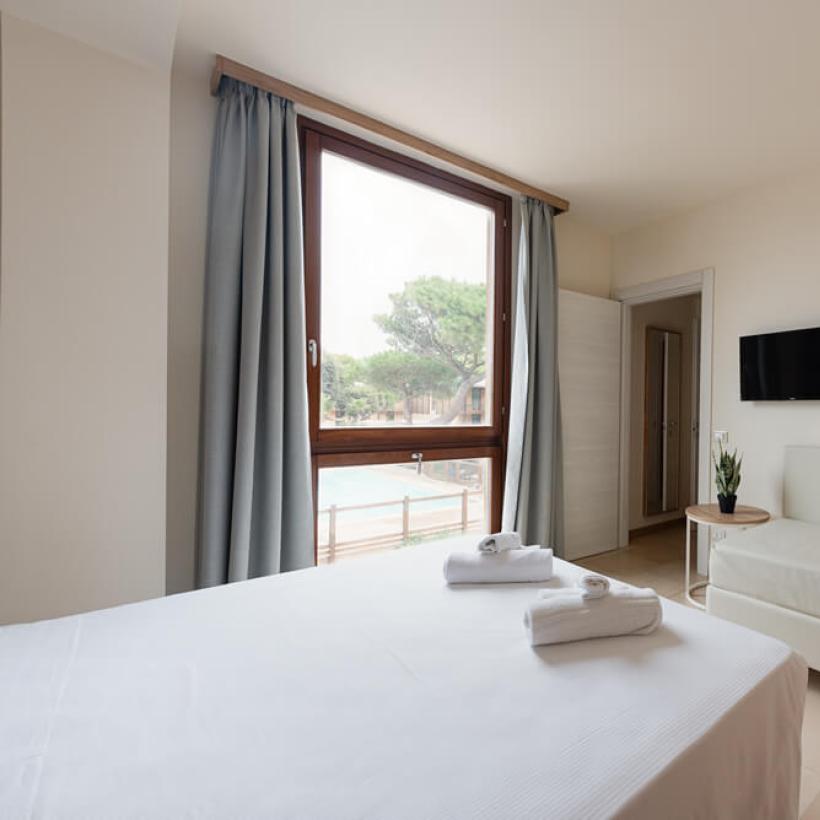 Modern room with bed, sofa, large window, and wall-mounted TV.